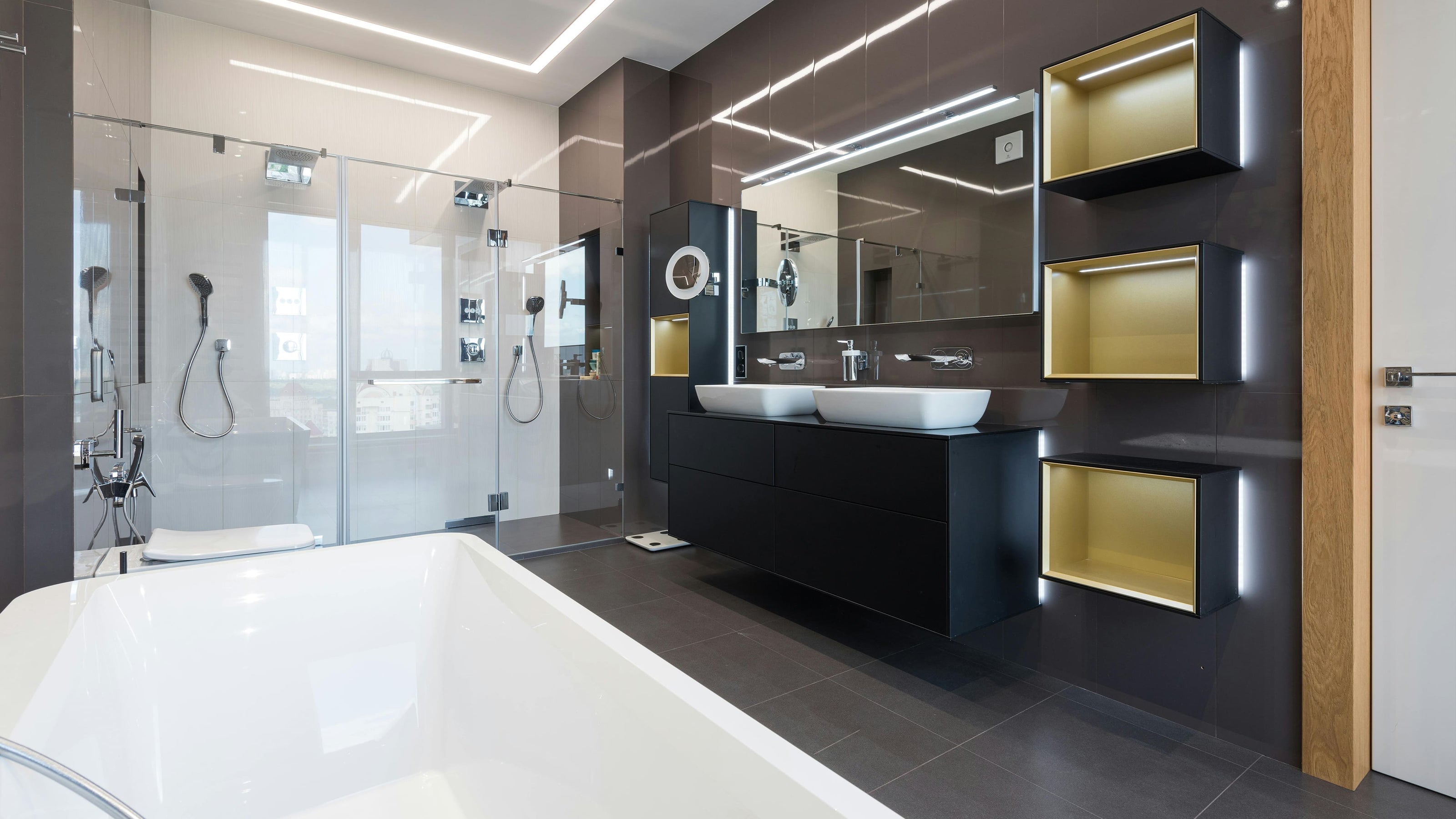 Bathroom renovation in Dubai featuring a modern luxury design with double sinks, glass showers, and sleek black and gold finishes.